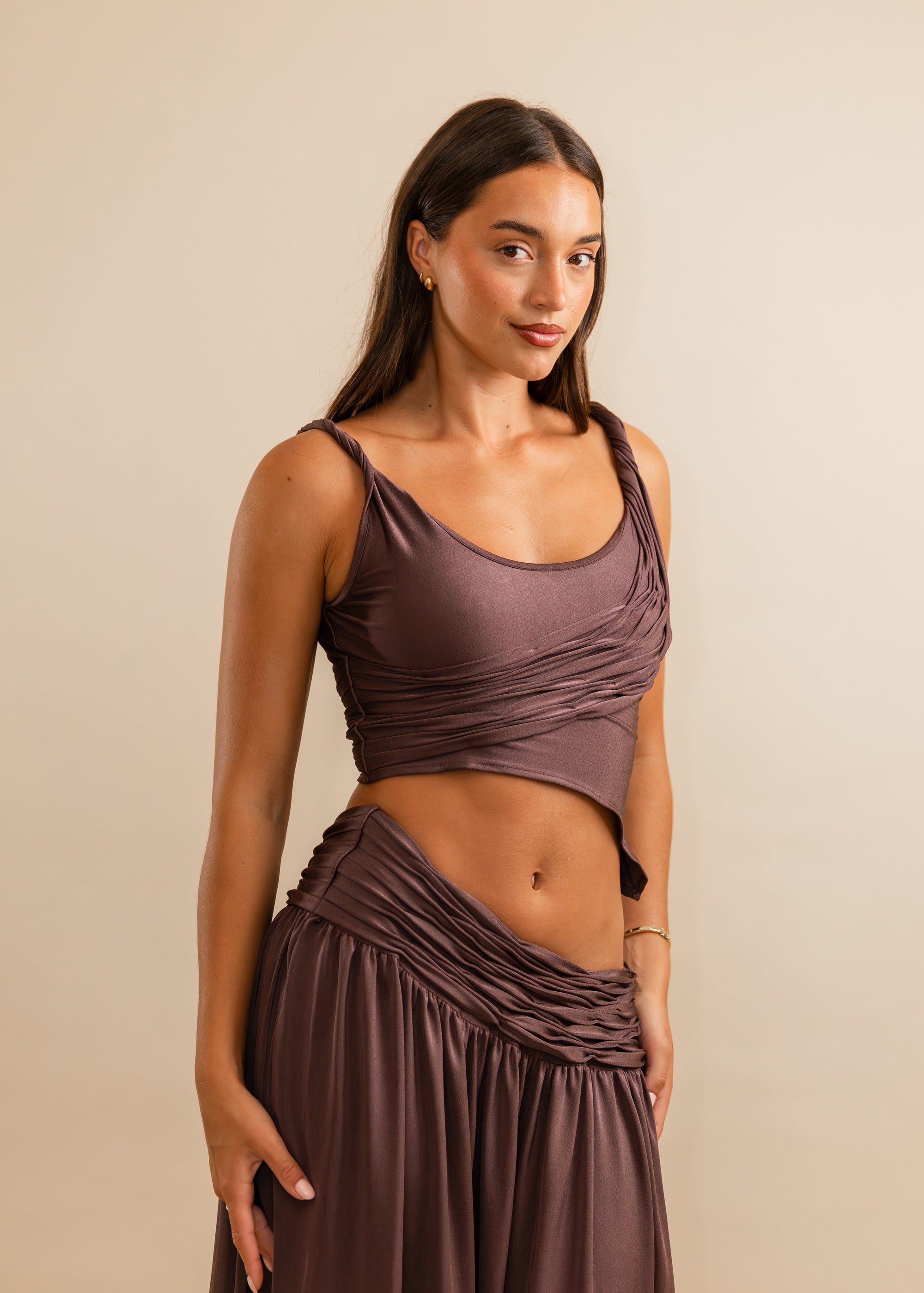 Woman wearing a plum sleeveless top and skirt set against a beige background