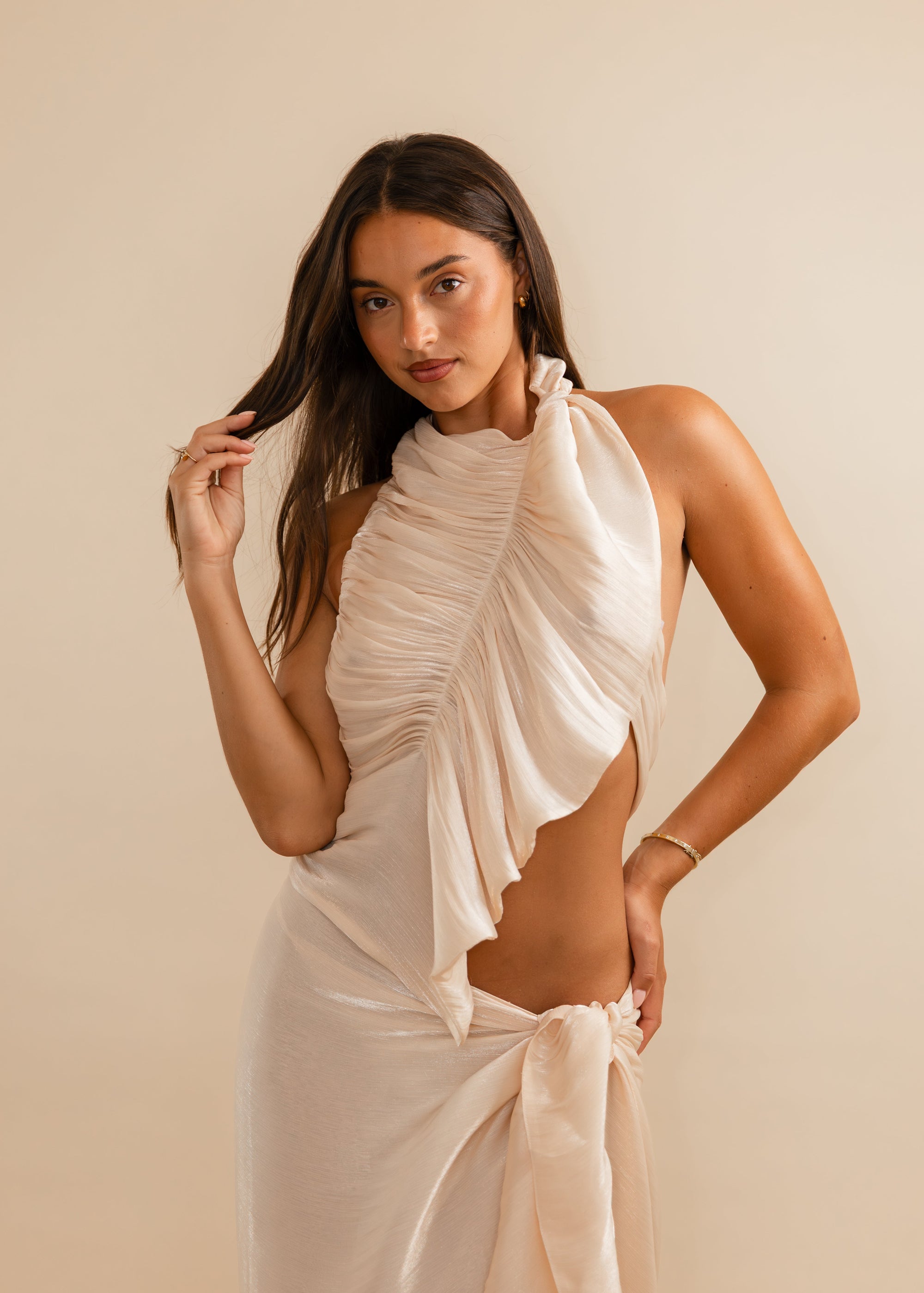 Women wearing champagne top against a plain background 