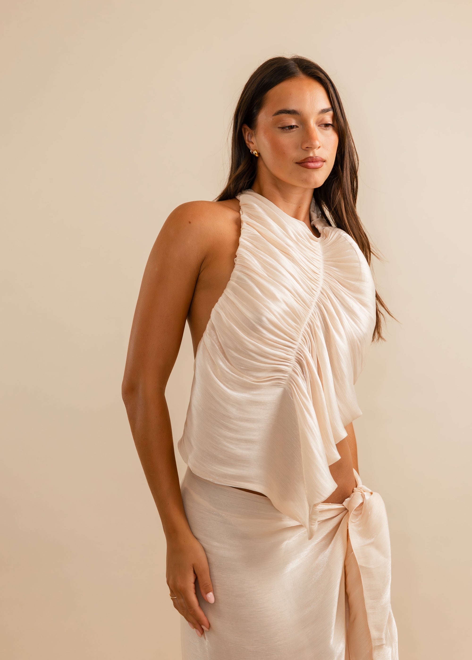 Women wearing a flowing champagne halter neck top and skirt 