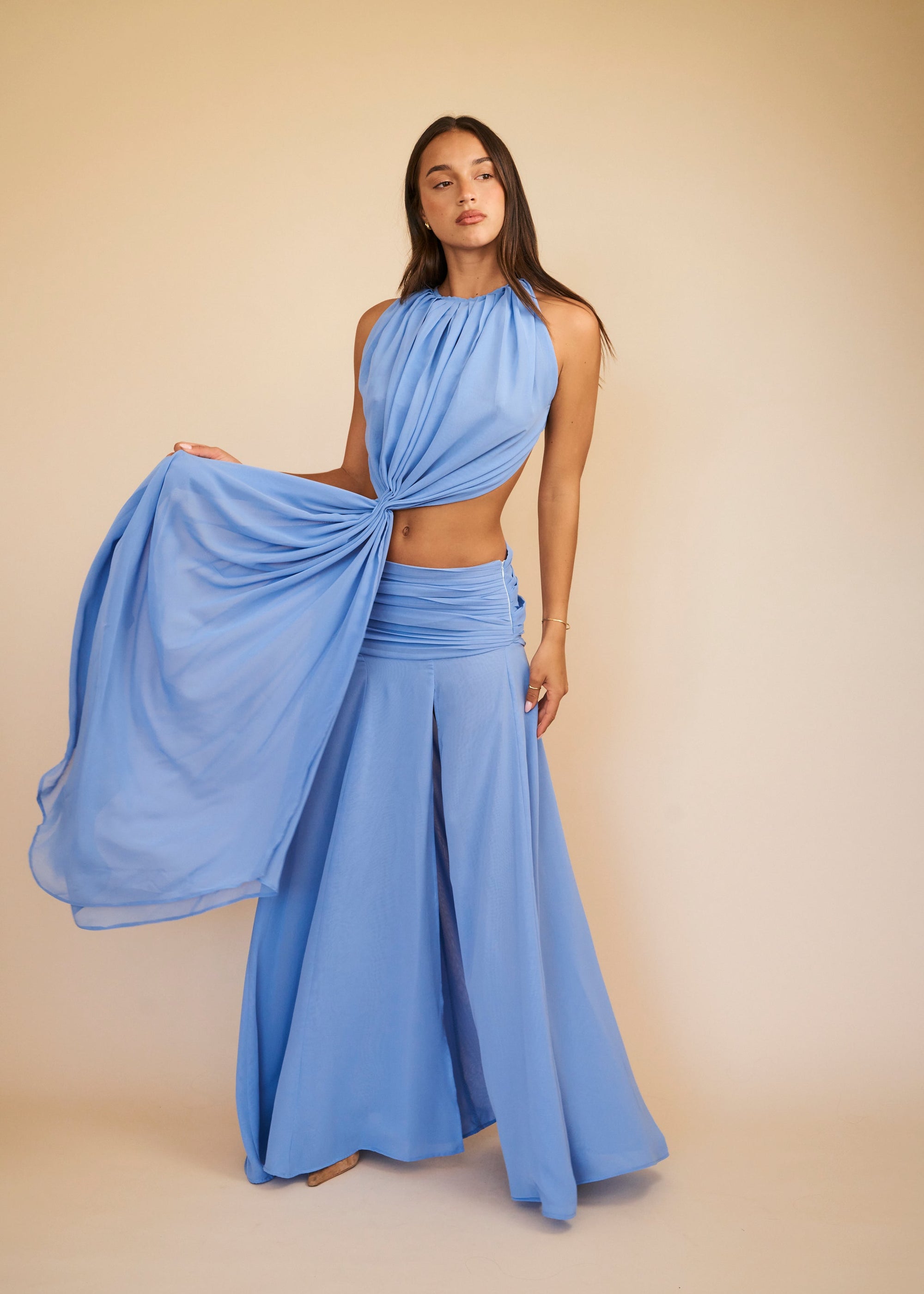 Woman wearing a blue dress with a flowing fabric on a beige background