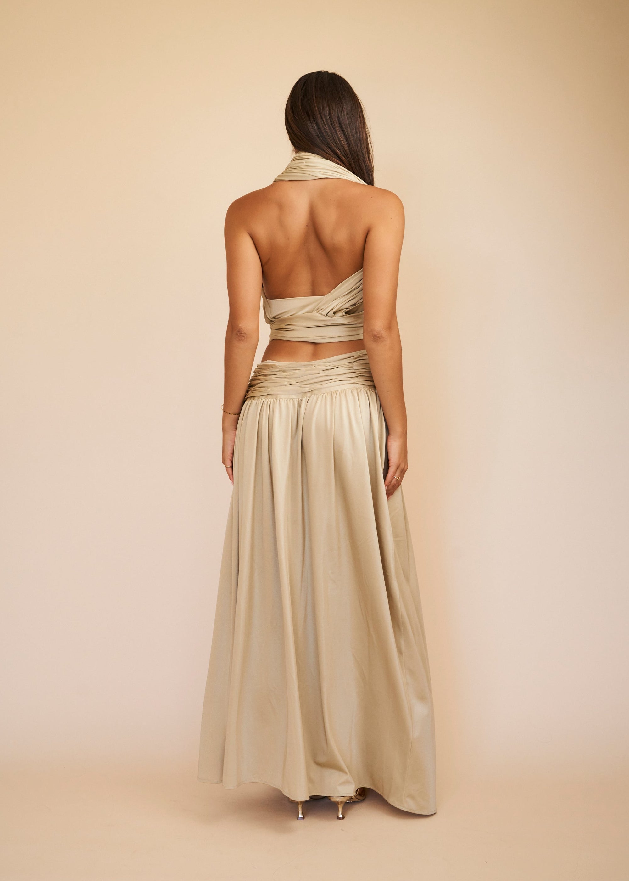 Woman wearing a flowing beige dress against a beige background