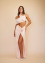 Woman wearing a white halter neck dress with a high slit on a beige background