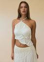 Woman wearing a white halter top and skirt set against a beige background