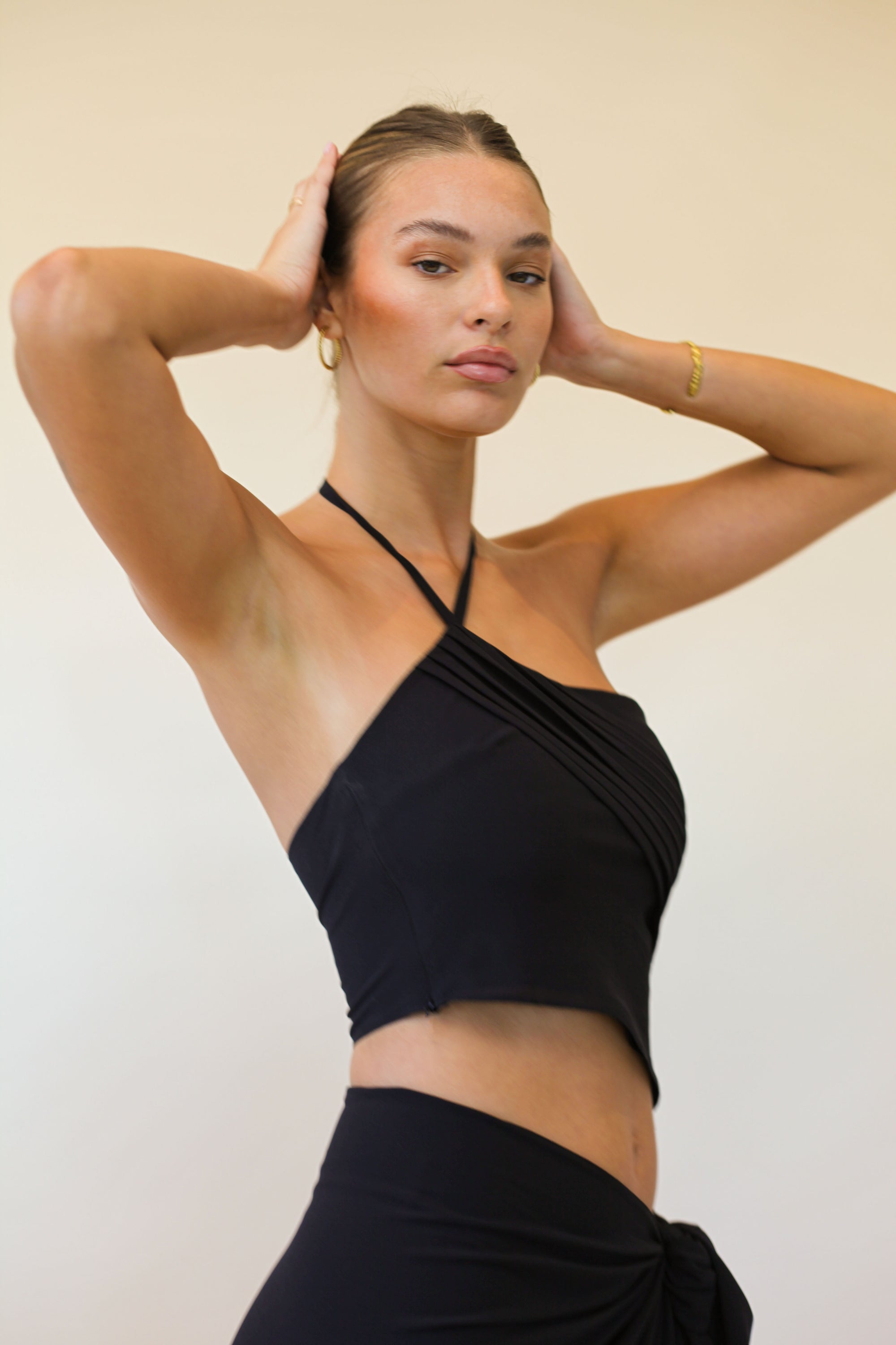 Woman wearing a black halter top and skirt against a plain background
