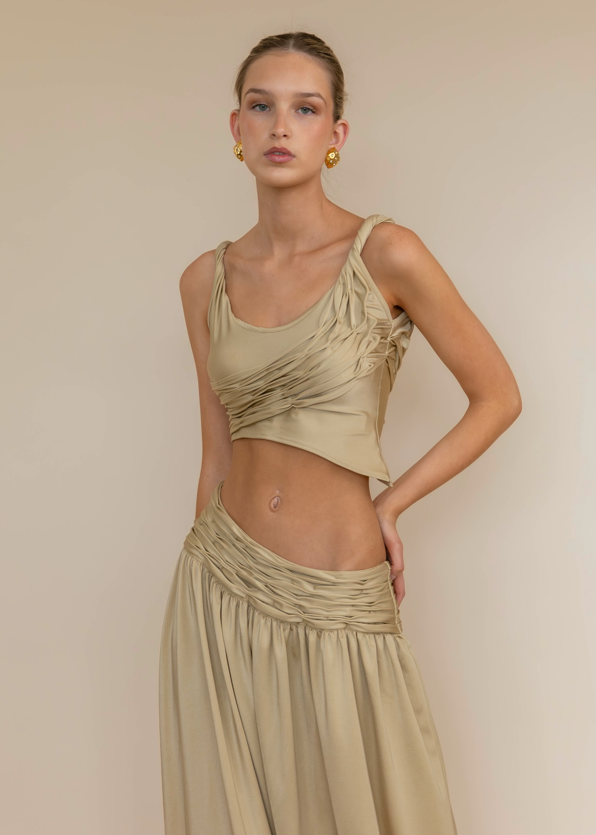 Woman wearing a beige top and skirt set against a plain background