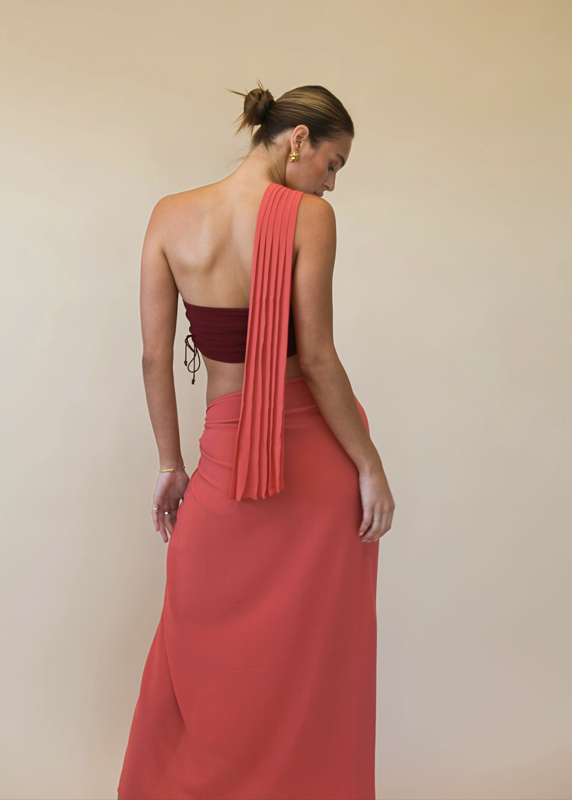 woman wearing a burgundy top with a orange sash