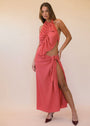 Woman wearing a coral orange halter neck dress with cut-out design and high slit on a beige background
